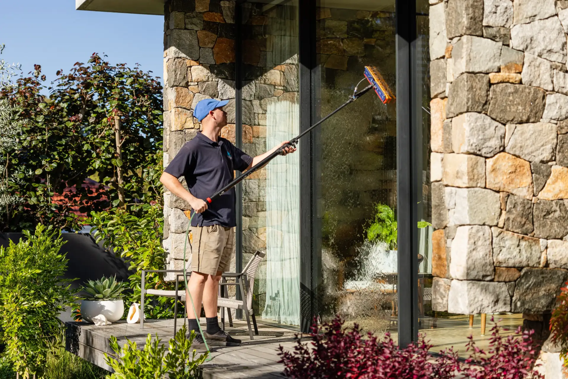 Water-fed brush cleaning the large windows of a stone house in Perth