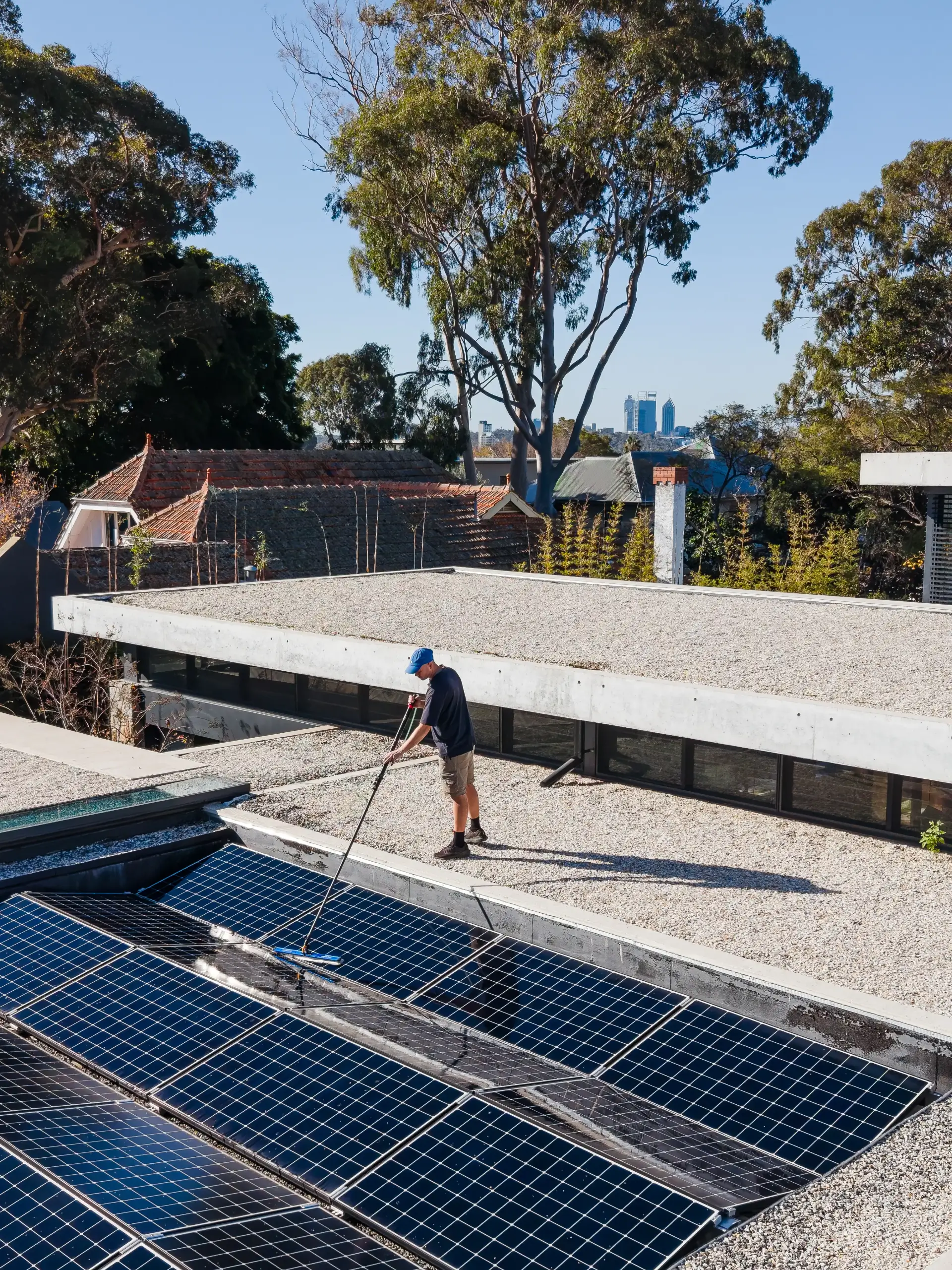 Solar panel cleaning with a long-handled brush on a Perth rooftop
