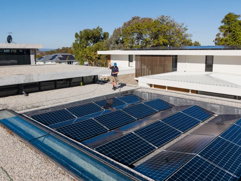 Technician inspecting rooftop solar panels before cleaning in Perth