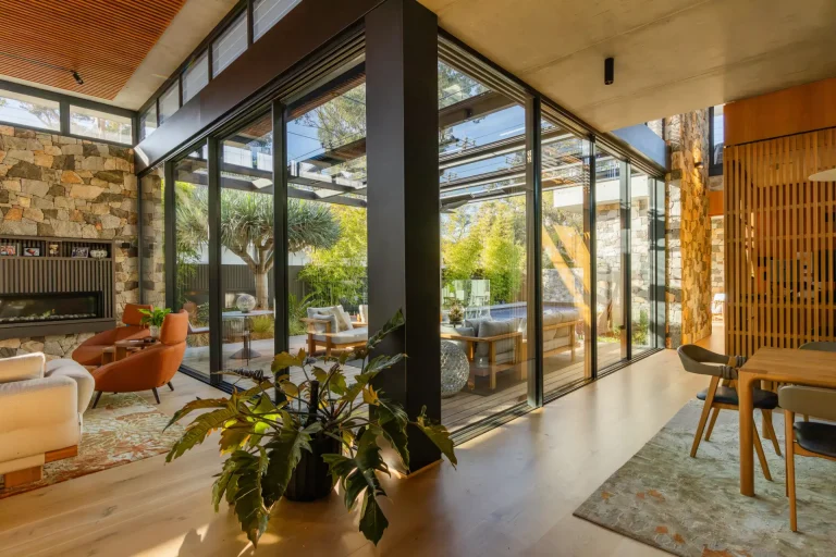 Sunlit living and dining area behind freshly cleaned glass walls