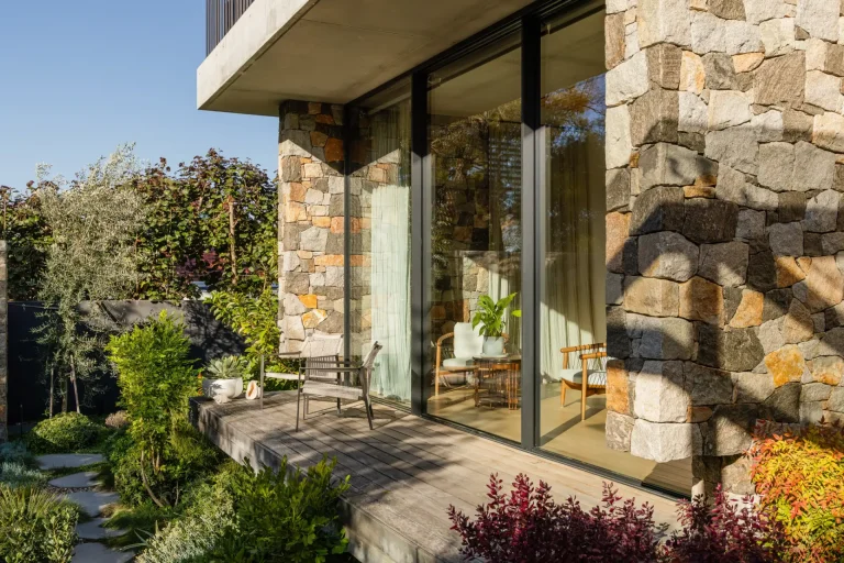 Modern stone house with freshly cleaned glass doors and wooden patio in Perth