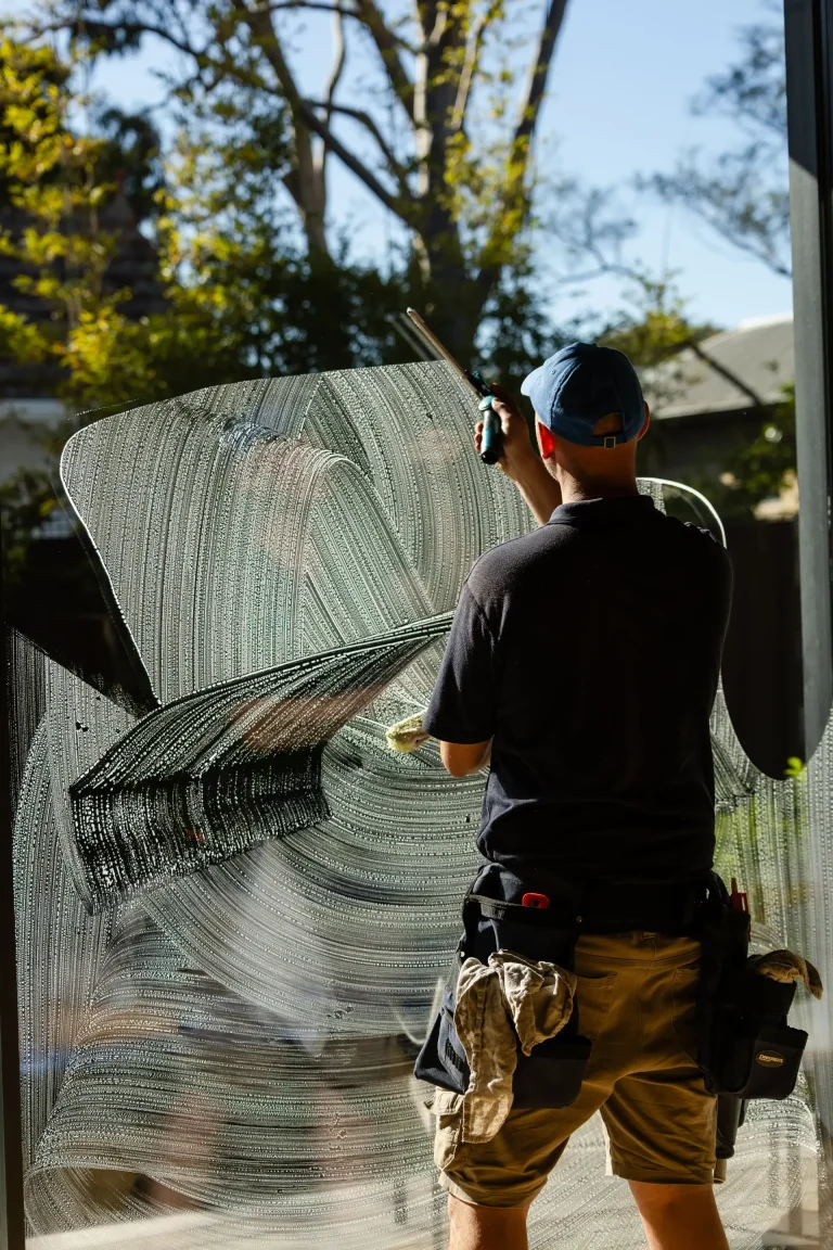 Soaping and squeegeeing a large window on a sunny Perth day