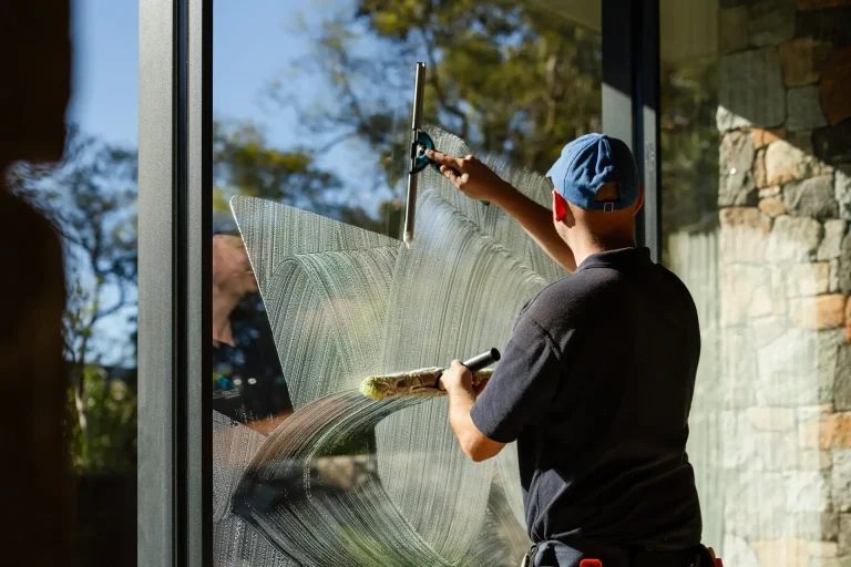 Soapy water and squeegee on a large window, trees and stone wall beyond, Perth