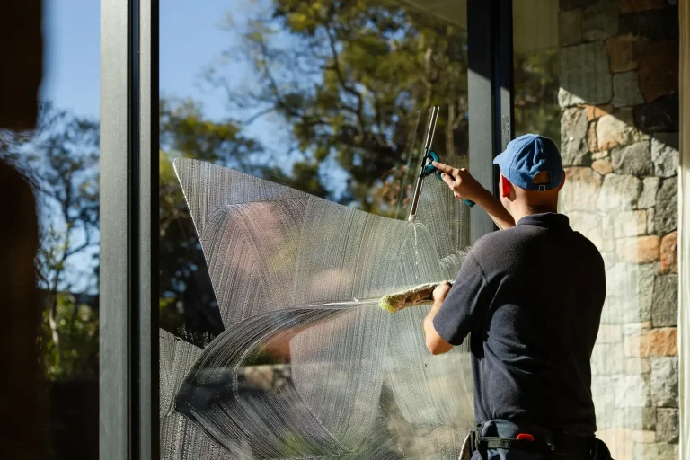 Window cleaner working soapy glass with a squeegee on a sunny Perth morning
