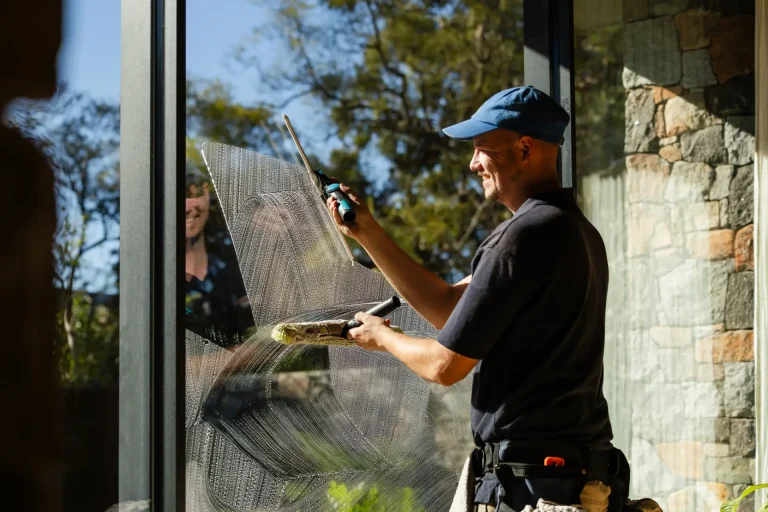Professional window cleaning with a squeegee under a sunny Perth sky