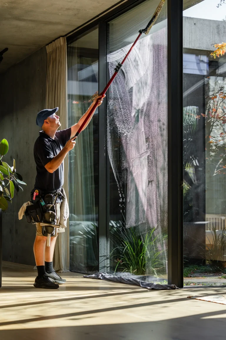Extension-pole cleaning of floor-to-ceiling glass inside a modern Perth building