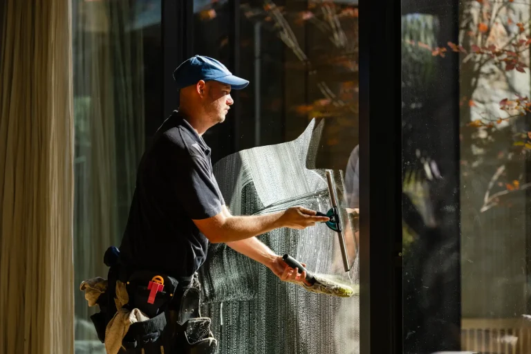 Uniformed window cleaner squeegeeing a large pane on a sunny day in Perth