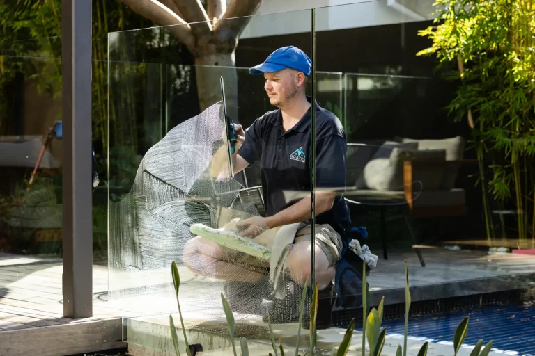 Detailing a glass pool fence panel with squeegee and pad at a Perth home