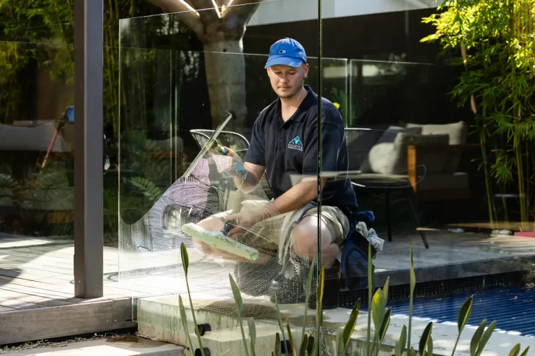 Glass pool fence cleaning by the water on a sunny day in Perth
