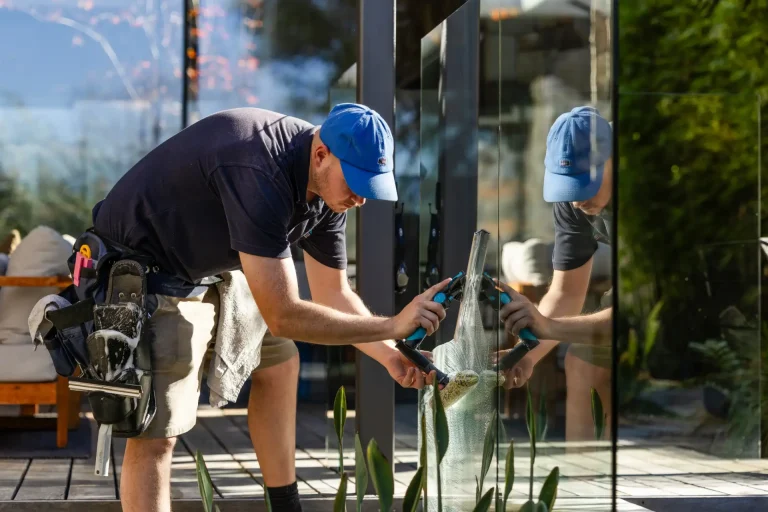Squeegeeing an outdoor glass panel with cleaning tools on belt in Perth