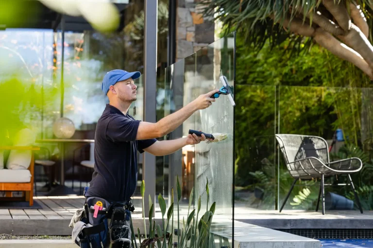 Squeegeeing an outdoor glass fence beside a leafy patio in Perth