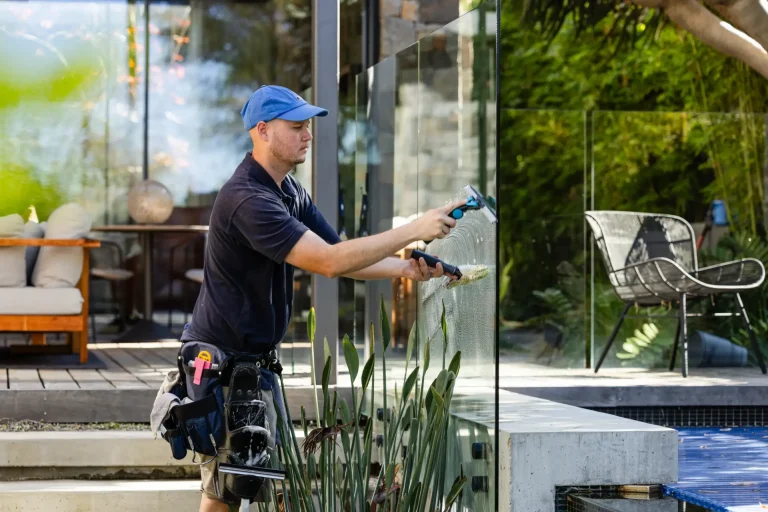 Glass fence cleaning with spray bottle and squeegee near a Perth patio